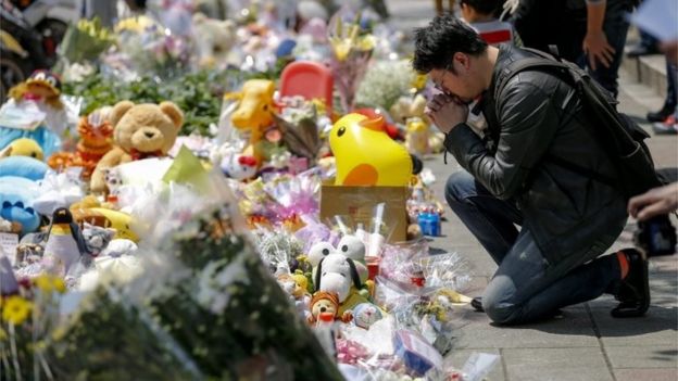A man offers flowers and prayers a four-year-old child victim of a random killing, at a makeshift memorial at a street next to the crime scene, in Taipei, Taiwan, 29 March 2016.
