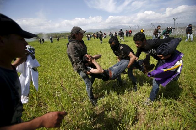 Migrants flee tear gas thrown by Macedonian police on the Greek border at Idomeni, 10 April