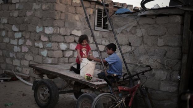 Palestinian children prepare food for a horse as they sit on a cart next to their house in El-Zohor slum on the outskirts of Khan Younis refugee camp, southern Gaza Strip