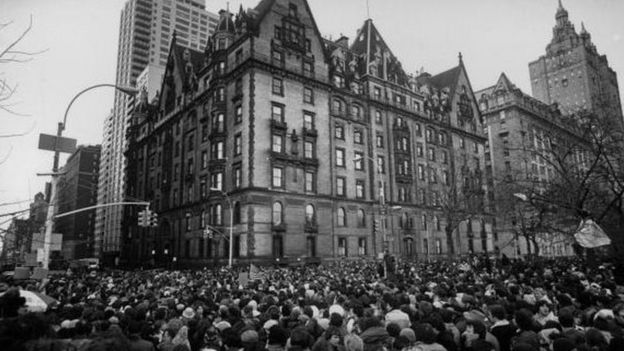 December 1980: Crowds gathering outside the home of John Lennon in New York after the news that he had been shot and killed. A flag flies at half-mast over the building