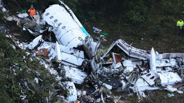 Rescue workers stand at the wreckage site of a chartered airplane that crashed in a mountainous area outside Medellin, Colombia, Tuesday, Nov. 29, 2016