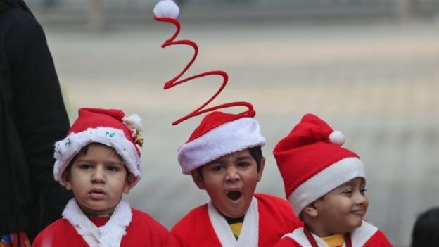 A child yawns as children wearing Santa Claus costumes take part in Christmas celebration in a school in Amritsar, India,