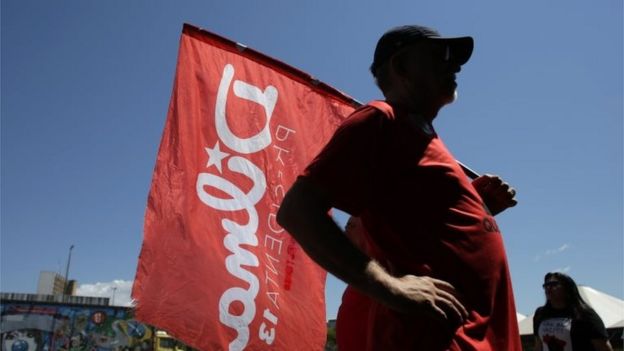 A man carries a banner with the name of Brazil's suspended President Dilma Rousseff at a camp in Brasilia, Brazil, Sunday, Aug. 28, 2016.