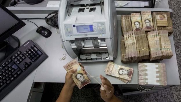 A bank worker counts 100 Bolivar bills in Caracas, Venezuela, 15 December 2016.