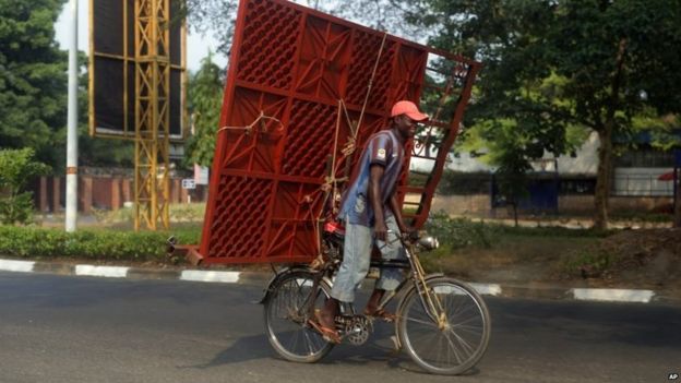 A cyclist carries a metal gate on the back of his bicycle in Bujumbura, Burundi (July 2015)