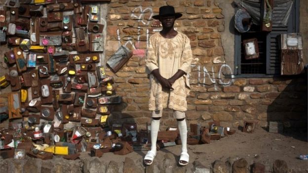 An artist poses by his pieces of art exposed during the Chale Wote street art festival in Accra, on 21 August 2016