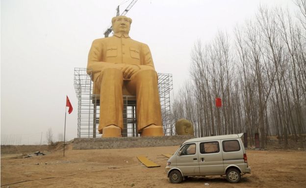 Mao statue towering over a car and trees