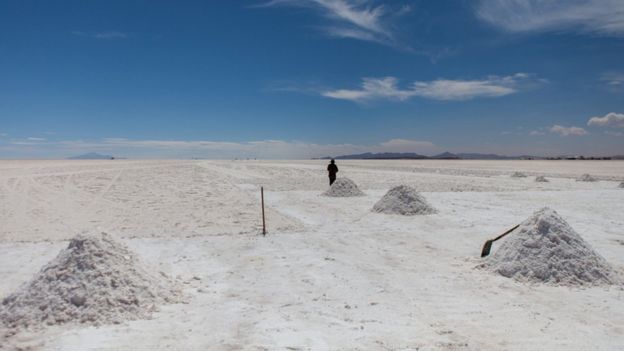 A man stands next to a pile of salt extracted from the ground