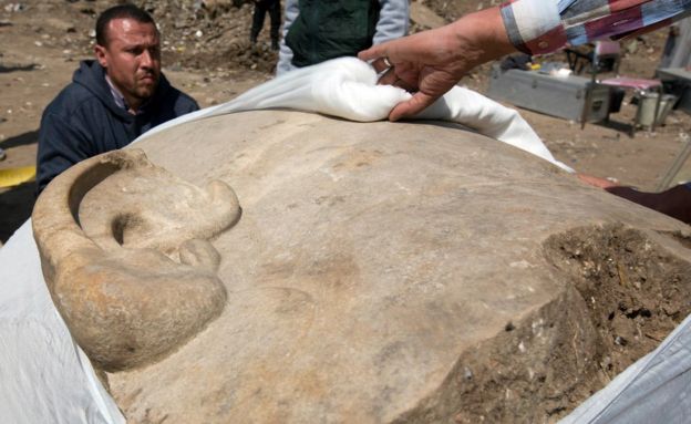 Antiquities workers cover the head of a massive statue, that may be of pharaoh Ramses II, one of the country