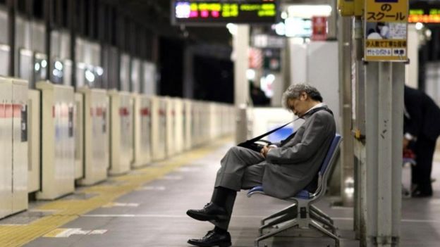 Un hombre dormido en un banco de una estación del metro