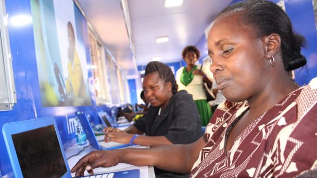 Women from a Nairobi slum area sit at a row of computers inside
