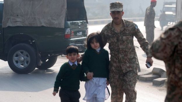 A Pakistani soldier escorts schoolchildren from the Army Public School when it was attacked by Taliban gunmen in Peshawar (16 December 2014)