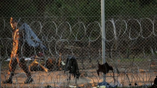 A Hungarian soldier patrols the razor wire fence at the Hungarian border with Serbia (12 September 2015)