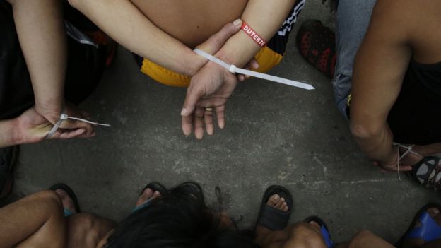 A Filipino drug suspect has his hands tied together during a police operation