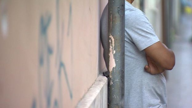A migrant boy standing next to a wall in Rome