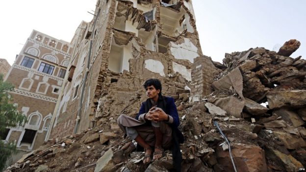 A Yemeni man looks on as a team of the International Committee of the Red Cross (ICRC) delegates inspects the scene of a Saudi-led coalition air strike in Sanaa's Old City (9 August 2015)