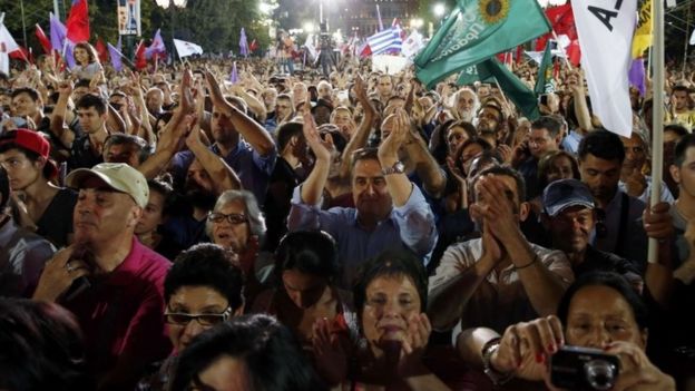 Supporters wave flags as former Greek prime minister and leader of leftist Syriza party Alexis Tsipras delivers his speech during the final campaign rally prior to Sunday's general elections at Syntagma square in Athens (18 September 2015)