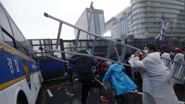 A protester hits a police bus with a ladder during the demonstration