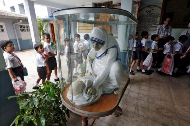 Escolares ante una vitrina con una escultura de la Madre Teresa en agosto de 2016