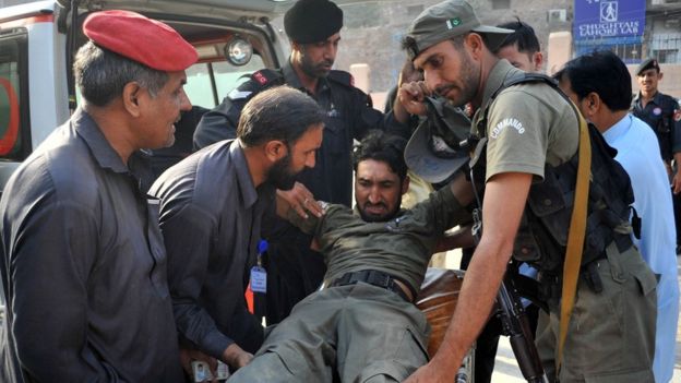 Pakistani security personnel help an injured comrade following an attack on a Pakistan Air Force base in Peshawar - 18 September 2015