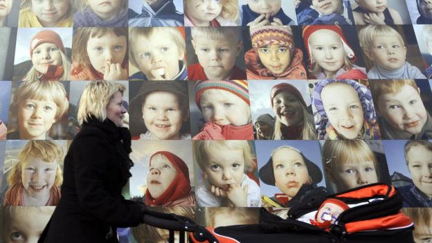 Una mujer pasa frente a un poster con rostros de niños en Islandia