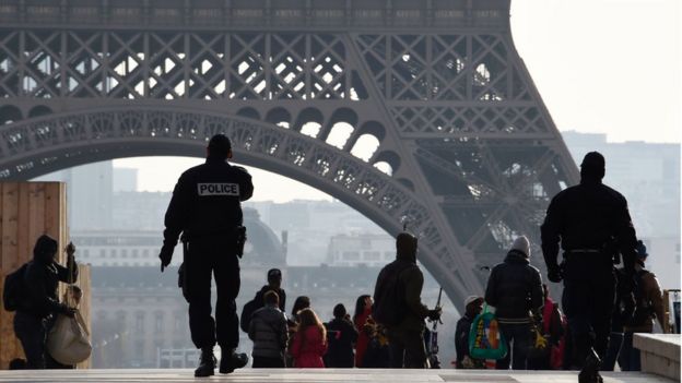 French police officers walk near the Eiffel Tower in Paris on December 24, 2015.