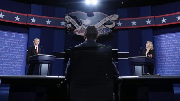 Students representing Donald Trump (L) and Hillary Clinton (R) and moderator Lester Holt (C) stand in position at the two podiums during a rehearsal the day before the first Presidential Debate, 25 September 2016