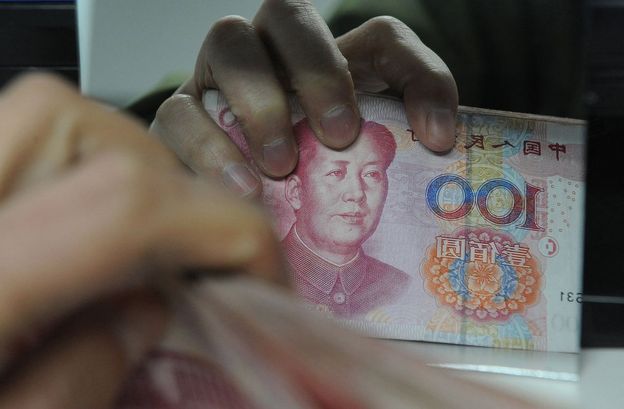 Chinese bank worker counts a stack of 100-yuan notes at a bank in Hefei, east China's Anhui province on 27 February 2011