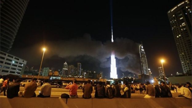 People watch as flames rip through the Address Downtown hotel after it was hit by a massive fire, near the world's tallest tower, Burj Khalifa, in Dubai, on December 31, 2015