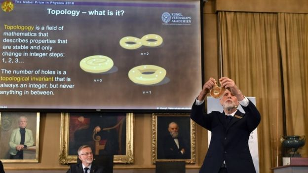 پروفسور تورس هانس هانسن پس از اعلام برندگان نوبل فیزیک معنای توپولوژی را با استفاده از تمثیل توضیح می‌دهد