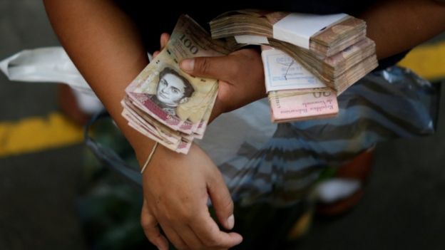 Man holding piles of Venezuelan banknotes