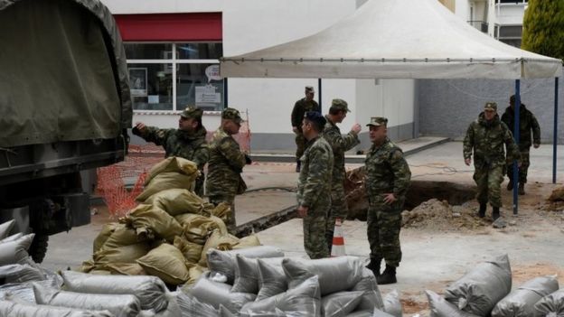 Military officers unload sacks of sand next to a hole in the ground (where a World War Two bomb was found in Thessaloniki (10 February 2017)