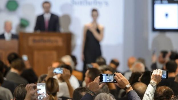 Spectators use their smart phones during the Sotheby's auction (11 November 2015)