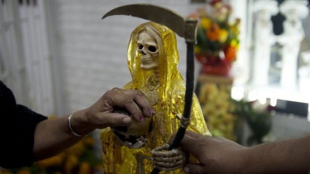 Devotees touch the figures of Santa Muerte (Saint of Death) before the central altar asking for favours during the main celebration in the market of one of the most dangerous neighbourhoods, known as Tepito in Mexico City, on 1 November, 2012.