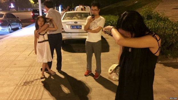 People stand in the street in Binhai, in the Tianjin area 12/08/2015