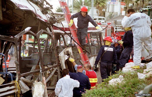 Israeli emergency and security personnel inspect a bus destroyed in a suicide bombing in Haifa on 2 December 2001