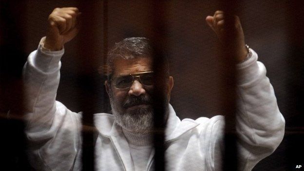 Mohammed Morsi gestures in the dock at a courtroom in Cairo, Egypt (3 March 2015)