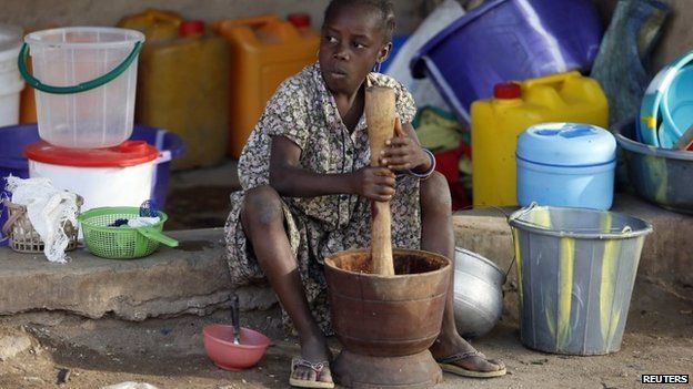 A girl displaced as a result of Boko Haram attacks in the northeast region of Nigeria, uses a mortar and pestle at a camp for internally displaced people in Yola, Adamawa State on 14 January 2015