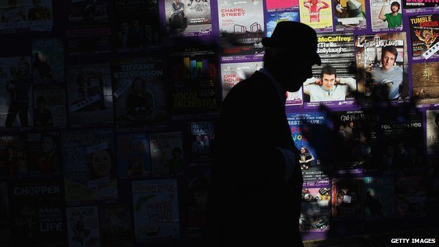 Man walks past a board promoting shows at the Edinburgh Fringe