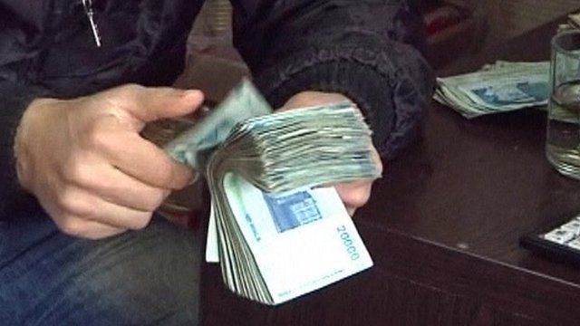 Man counting wad of rial notes