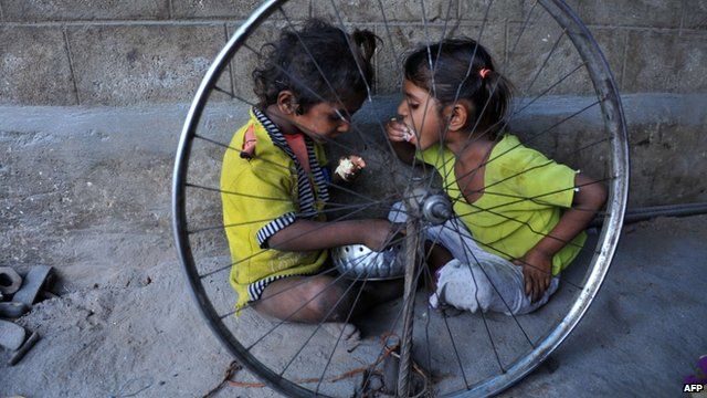 Indian children eat food at their temporary shelter on the side of a road in Hyderabad