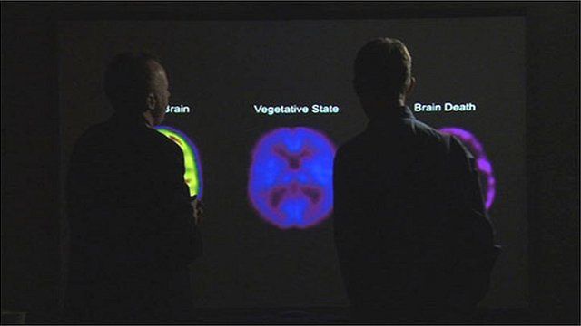 Prof Owen in front of PET brain scans