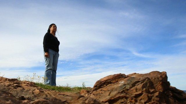 Woman on rock staring out to sea