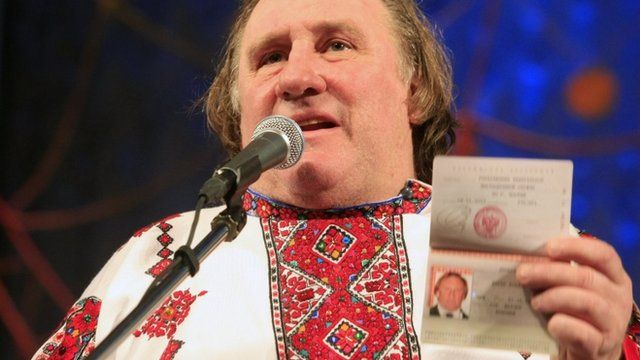 Gerard Depardieu, wearing a local costume, shows his passport