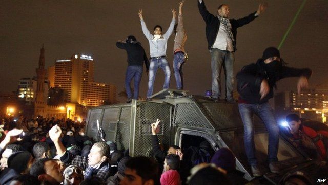 Protesters climb on top of a police vehicle in Tahrir Square, Cairo (28 January 2013)