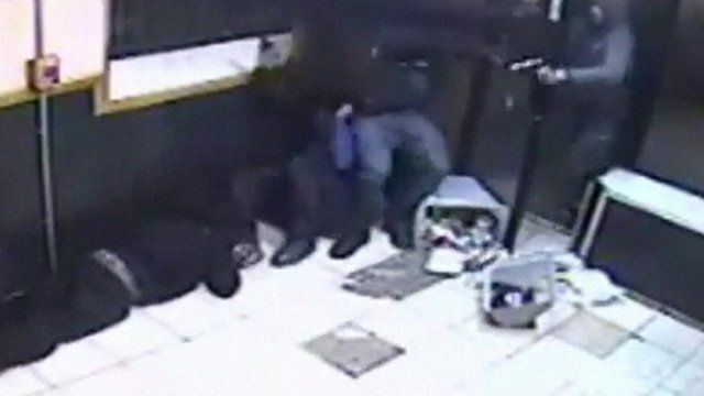 Gunman (far right) tries to shoot as several men try to keep the door closed