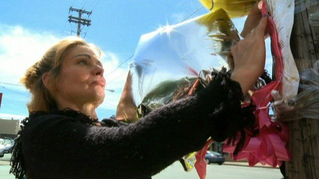A woman decorates Lorain Avenue, Cleveland, with balloons after three women that went missing there were found alive on Monday