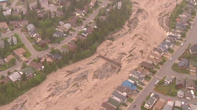 Muddy flood water flows through a creek in Alberta