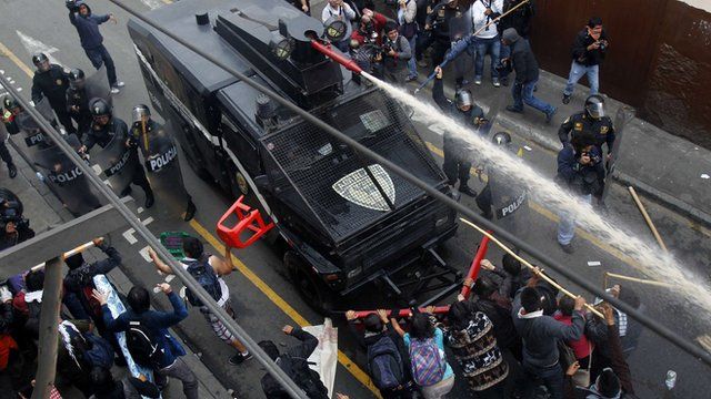 Students try to push a police truck as they clash with riot police in Lima