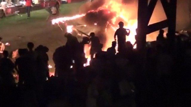 Crowds moving away from the burning firework display